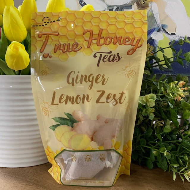 bag of ginger lemon tea bags surrounded by greenery and flowers.