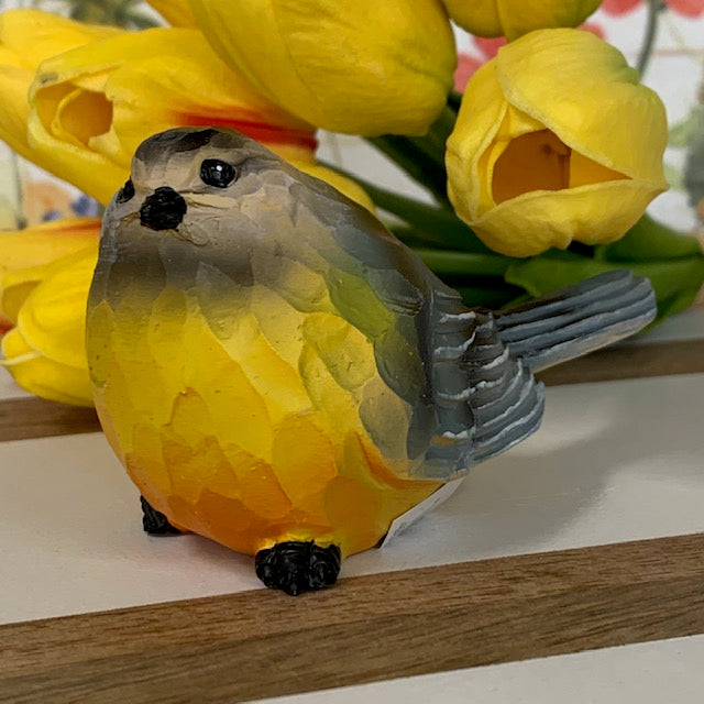 gray bird sitter displayed next to yellow tulips