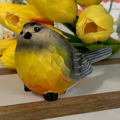 gray bird sitter displayed next to yellow tulips