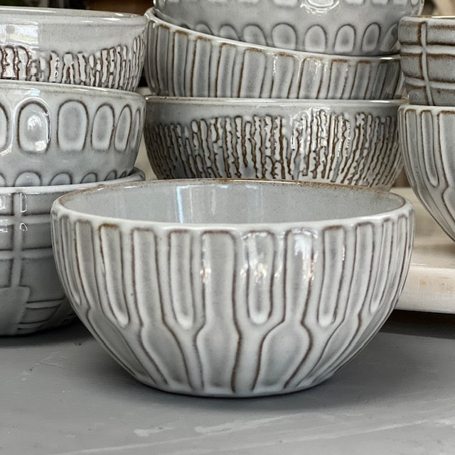 columns patterned stoneware bowls displayed in front of multiple patterned stoneware bowls on a white surface