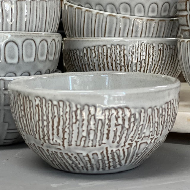 ridges patterned stoneware bowls displayed in front of multiple patterned stoneware bowls on a white surface