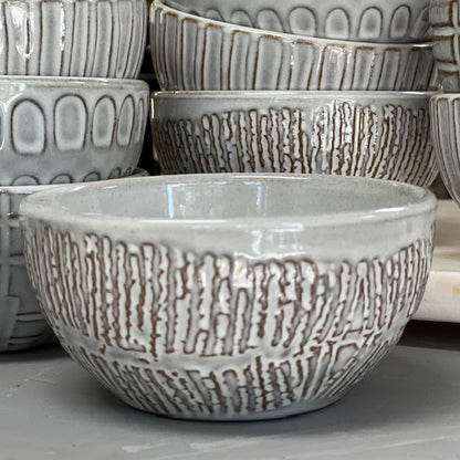 ridges patterned stoneware bowls displayed in front of multiple patterned stoneware bowls on a white surface