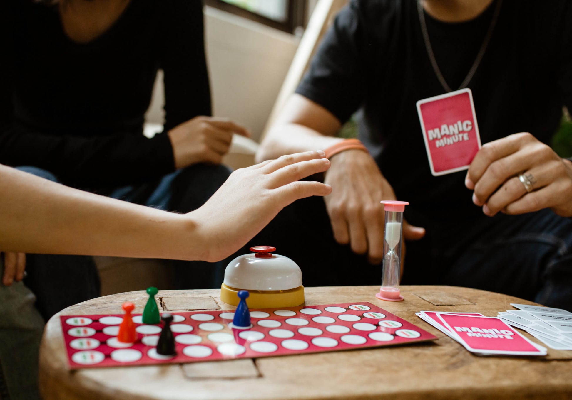  game pieces set up on wooden coffee table with hands playing game.