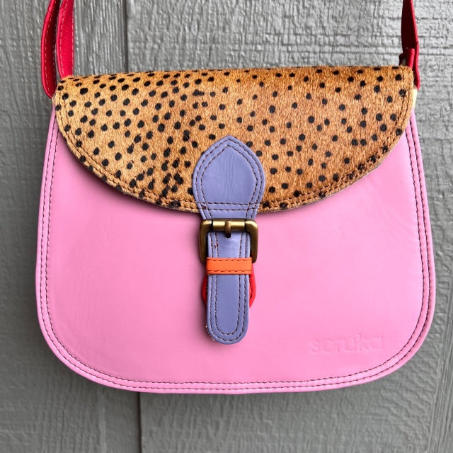pink purse with black and brown animal print flap, lavender buckle, and red strap.
