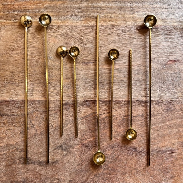 mulitple sizes of the harper gold spoons displayed on a wooden table