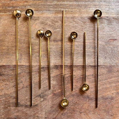 mulitple sizes of the harper gold spoons displayed on a wooden table