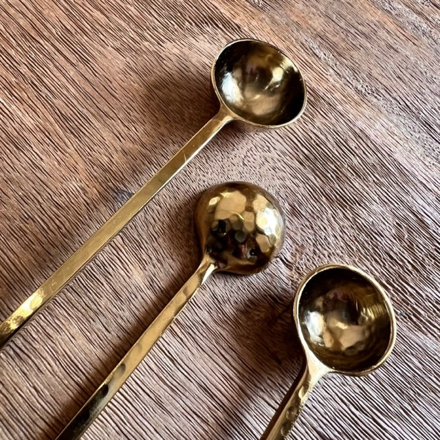 close up view of three harper gold spoons on a wooden surface