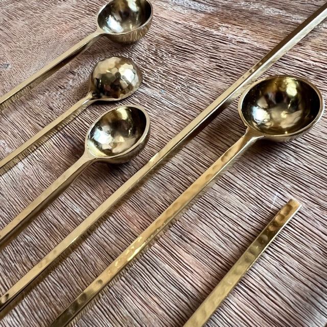 angled view of six harper gold spoons on a wooden surface