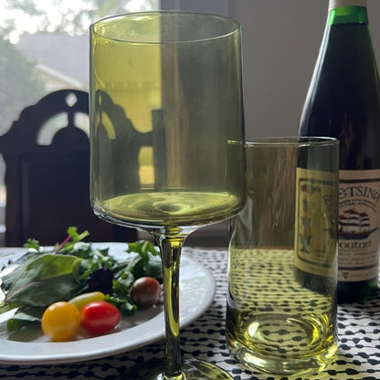 olive mid century cooler glass displayed on a black and white table cloth next to a plate of salad a water glass and a bottle of wine