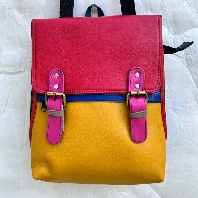 yellow backpack with red flap, pink buckles, and red trim.