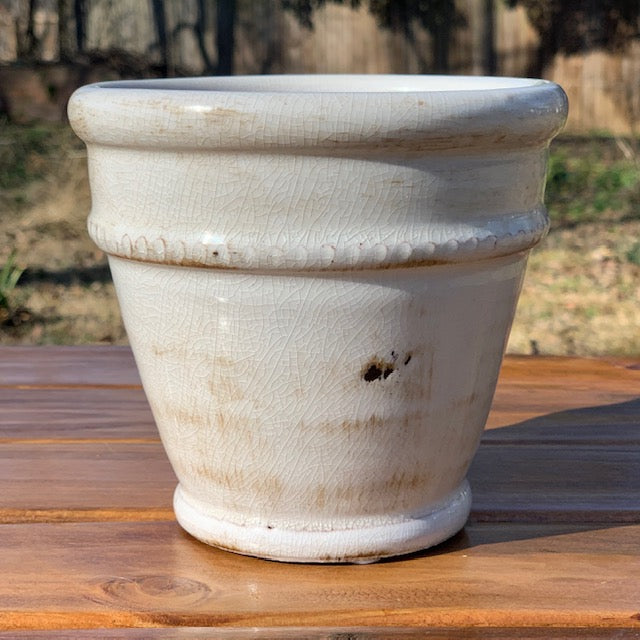rimmed glazed ceramic pot displayed on a wooden picnic table outside