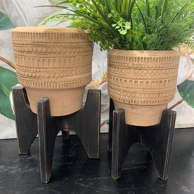 small and medium planter with stands displayed with greenery inside on a black table against a floral picture