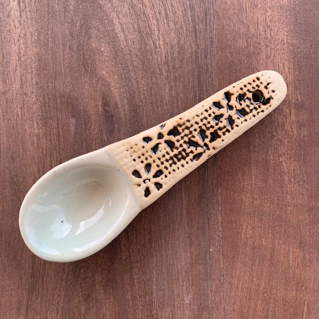 lattice floral hand painted stoneware spoon on a dark wood background