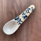 blue vines hand painted stoneware spoon on a dark wood background
