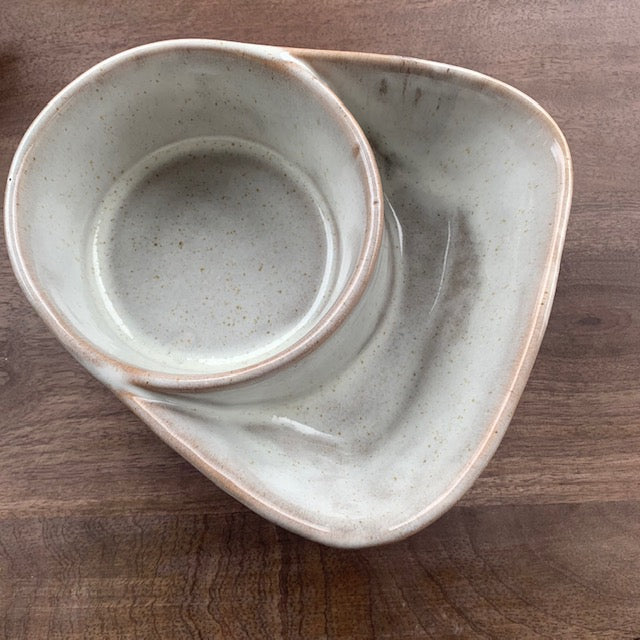 cream stoneware cracker and soup bowl on a dark stained wood surface