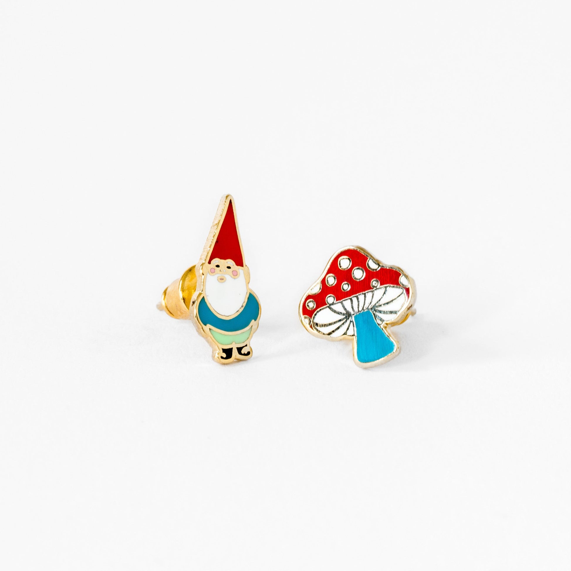 pair of earings, one a gnome, one a mushroom, on white background.