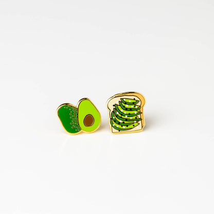 pair of mis-matched earrings, one avocado, one avocado toast, on white background.