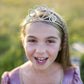 a young girl wearing the gold glitter tiara in a field