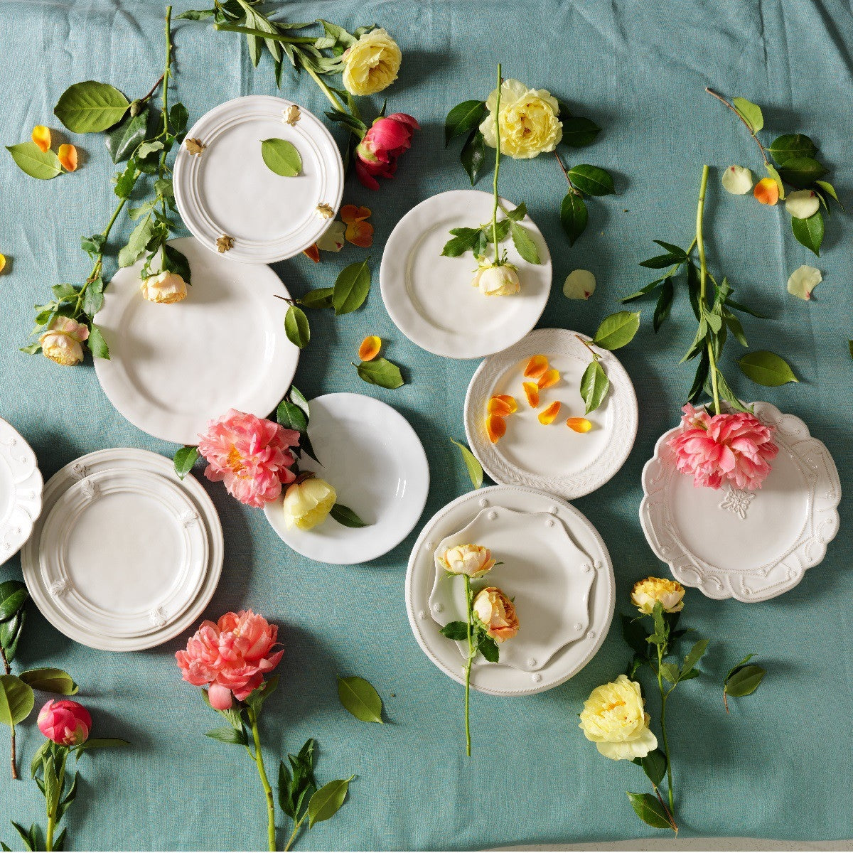 juliska plates scattered on a teal tablecloth surrounded by flowers