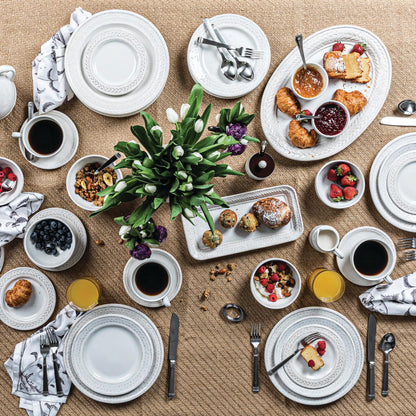 table display with the le panier hostess tray, oval platter, dinner plates, salad plates, mug and saucer set, vase with flowers on a tan tablecloth