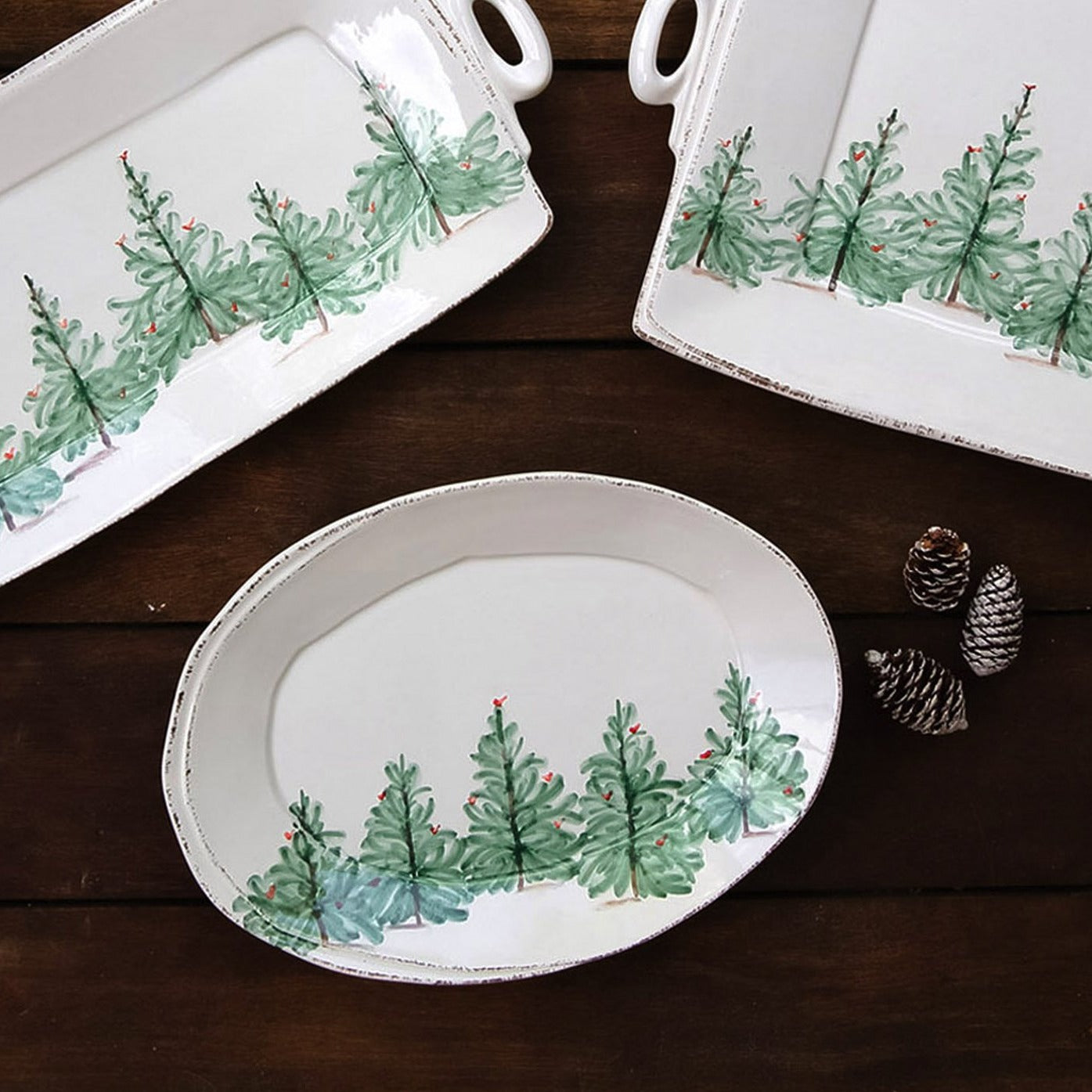 holiday platters and pinecones arranged on wooden tabletop.