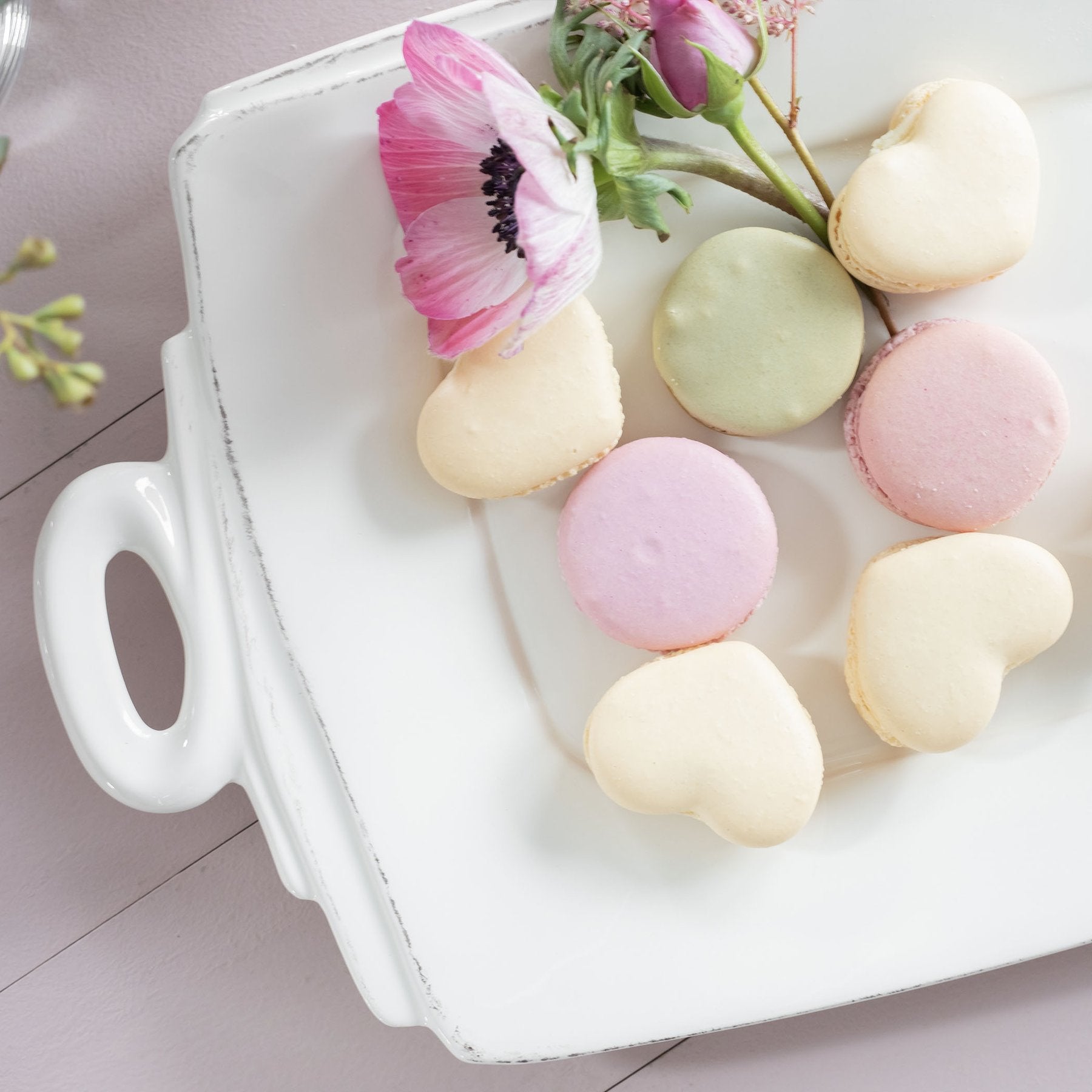 platter filled with cookies and flowers on wooden tabletop.