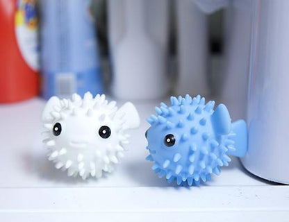 white and blue puffer fish dryer buddies displayed in front of laundry detergents on a white surface
