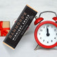 the midnight snack milk chocolate candy bar displayed next to a red clock and wrapped package on a white background
