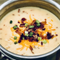 a pot of loaded baked potato soup on a rustic wood surface