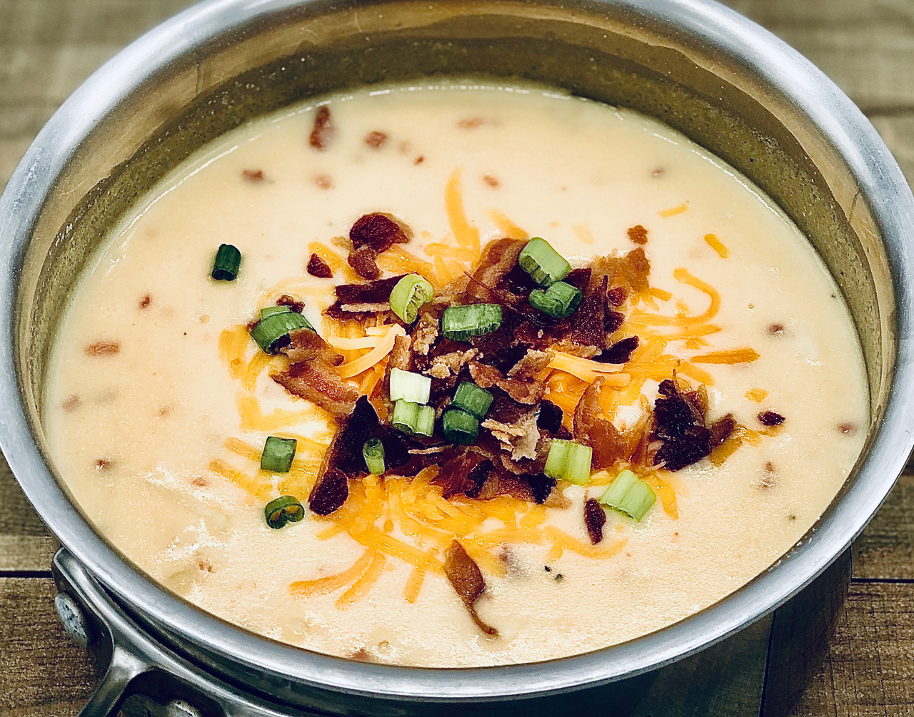 a pot of loaded baked potato soup on a rustic wood surface