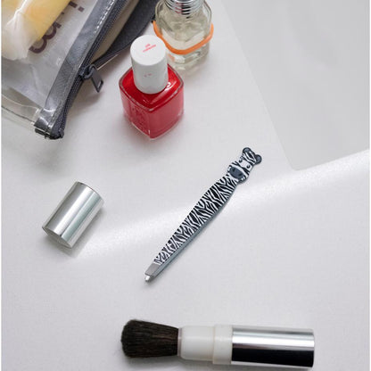 zebra safari tweezers displayed next to nail polish makeup brush and zipper bag on a white background