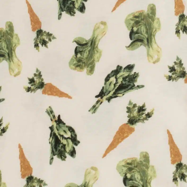 close-up of fabric of cream footed sleeper with all-over pattern of carrots and greens.