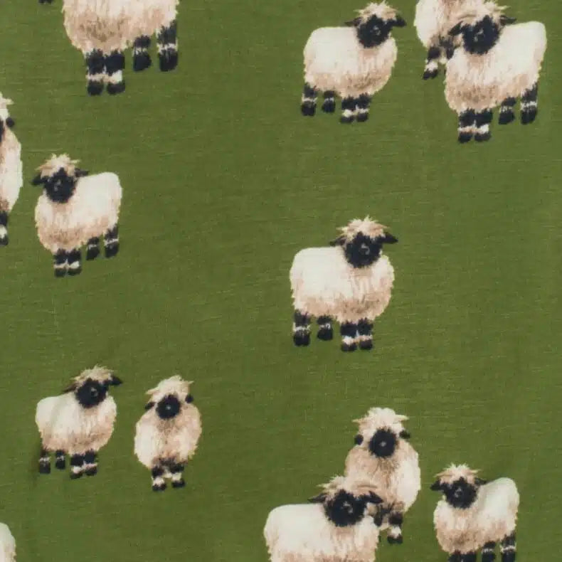 close-up of fabric pattern of green footed romper with all-over pattern of sheep.