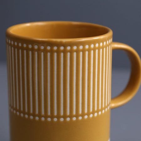 close-up of mustard yellow mug with dot and line pattern.