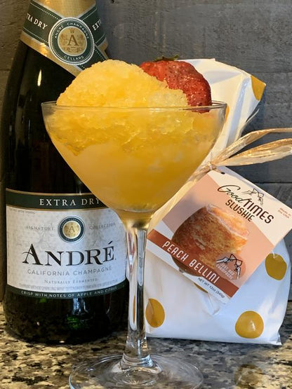 peach bellini slushie in a glass displayed next to the package and bottle of champagne on a granite countertop