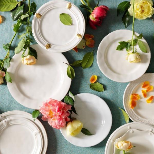 a display of white plates surrounded by flowers  on a teal background