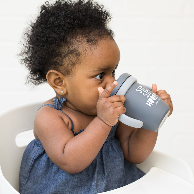 baby girls using happy sippy cup against a white background