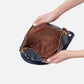 a person hands showing the inside view of the sapphire merrin convertible backpack shoulder bag on a white background