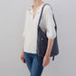 a woman wearing the sapphire merrin convertible backpack shoulder bag on her shoulder against a light gray background