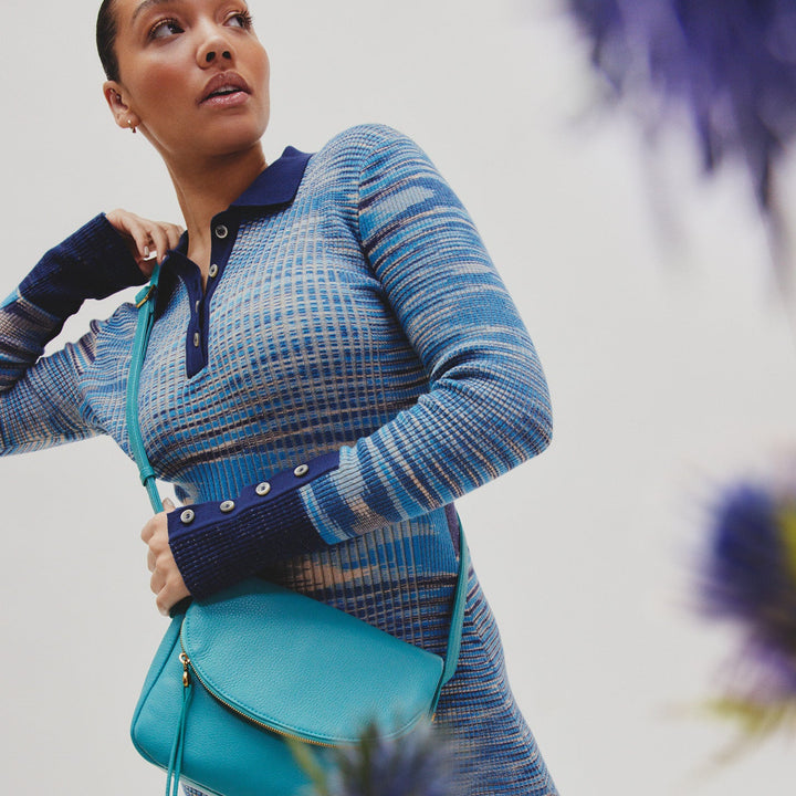 woman wearing a blue sweater with the aqua fern bag across her shoulder.