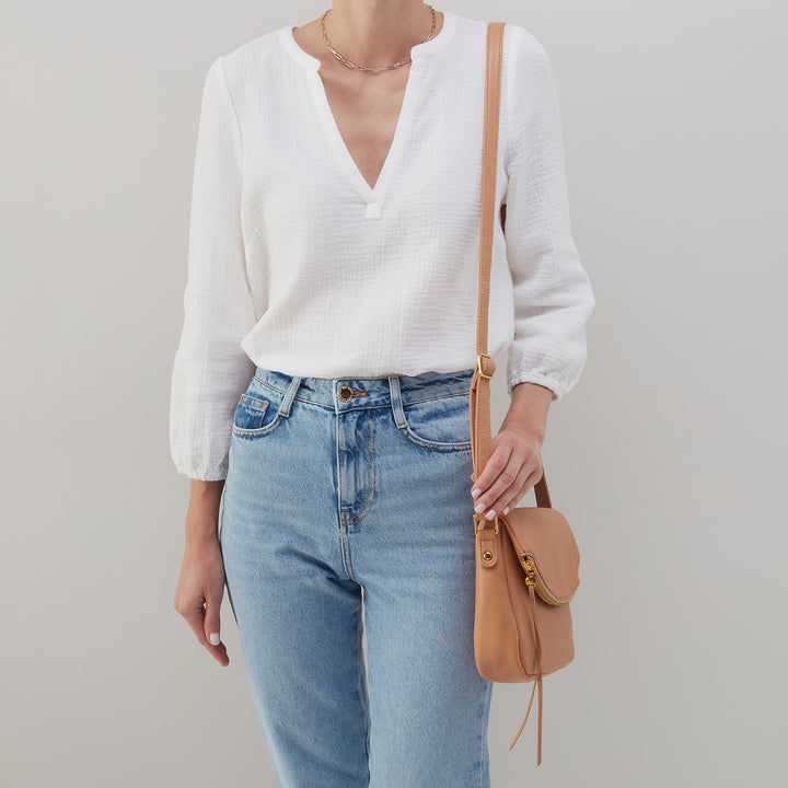person wearing white shirt, blue jeans, and sandstorm fern bag.
