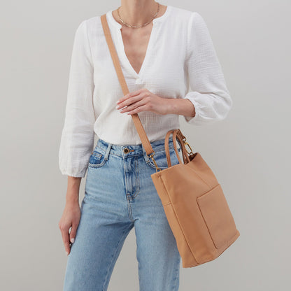 person wearing jean and white blouse with tripp tote over sholder.