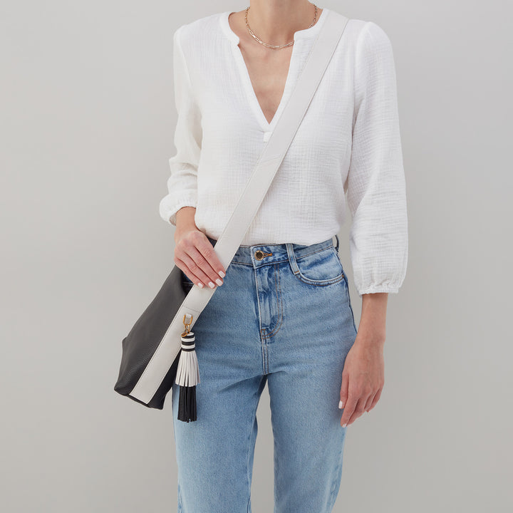woman wearing jeans and a white top with blaze bag over her shoulder.