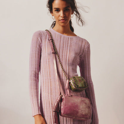 woman wearing a blush pink top with a metallic violet renny bag over her shoulder.