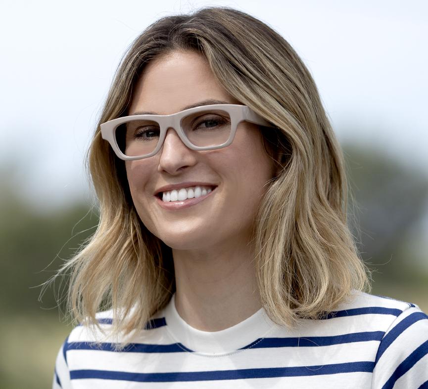 angled view of a woman modeling the  taupe scandi glasses while standing outside