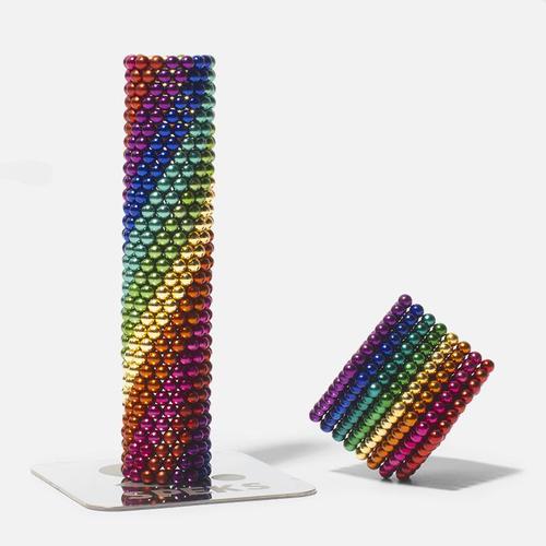 cylinder stack of rainbow colored speks magnet balls and a cube made from rainbow colored magnetic balls on a white background.