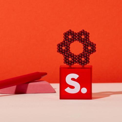 flower shape made from red magnetic balls on a small acrylic stand on a red background.