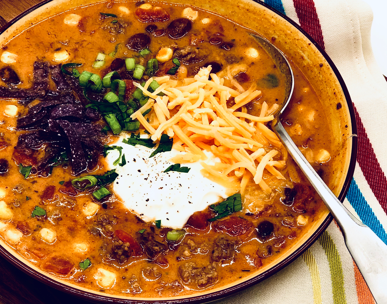 a bowl of tasty taco soup with cheese and sour cream sitting on a towel