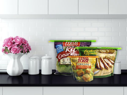 three different food bags closed with the bag sealers displayed on a kitchen counter next to a vase with flowers