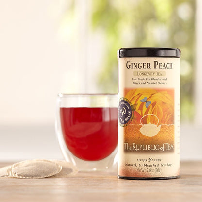 ginger peach black tea canister displayed on a table next to a glass of tea and tea bags